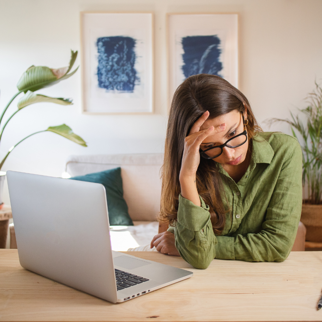 woman working near a laptop with her hand on her head while she looks away, looks stressed